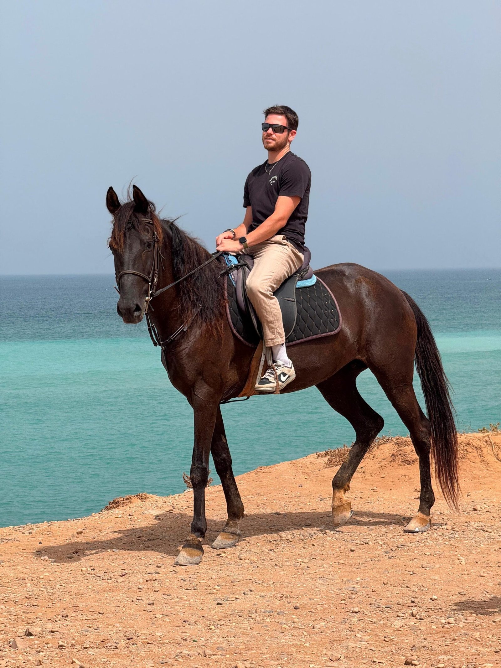 2-day horse trek near Agadir — a rider on the red-earth cliff-top trail above the Atlantic, Aourir, Morocco