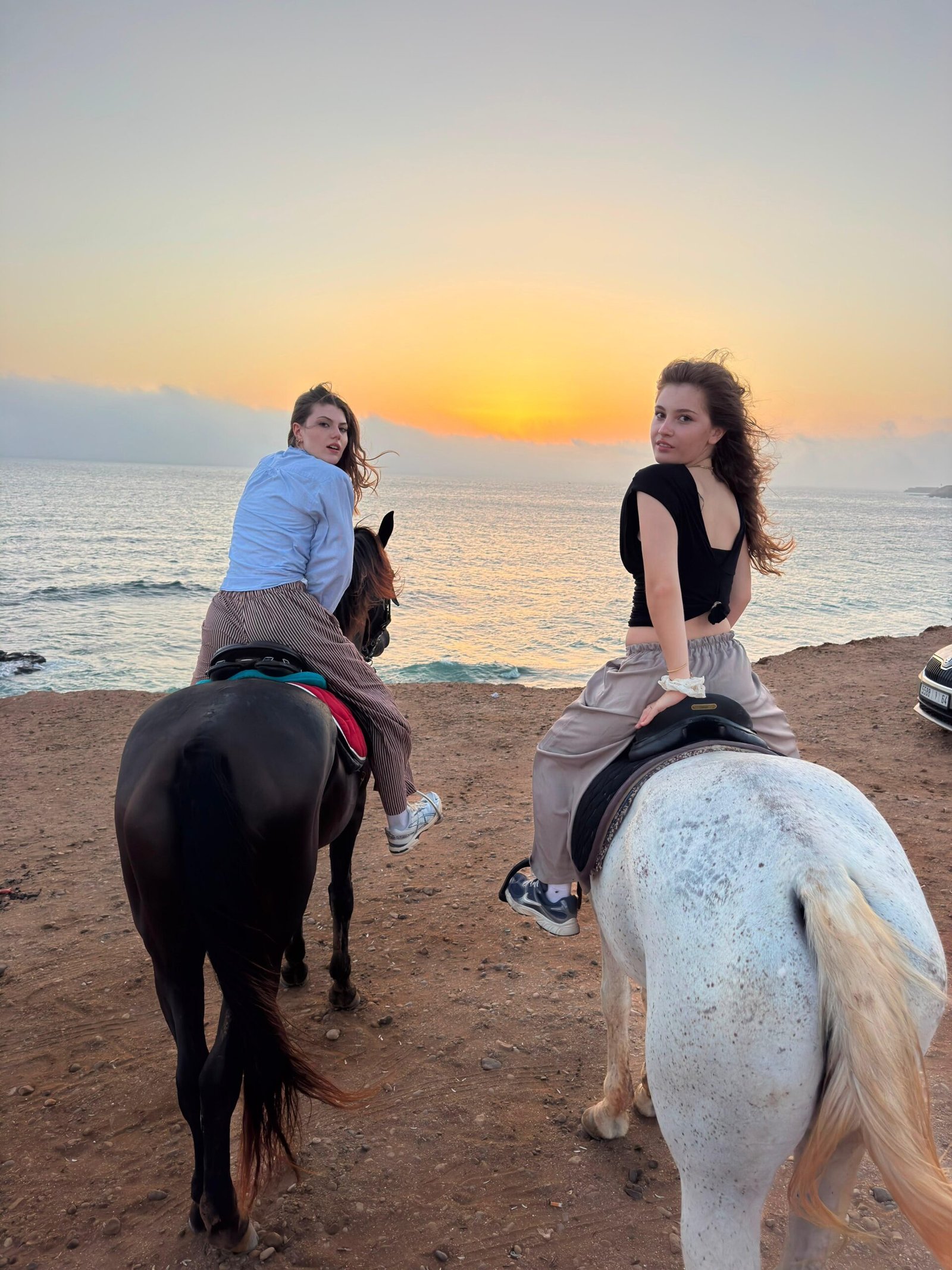 Horse riding Taghazout — two riders on Banana Beach at golden hour